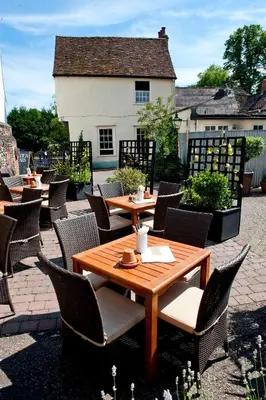 a wooden table and chairs on a patio at The Fox by Greene King Inns in Bury Saint Edmunds