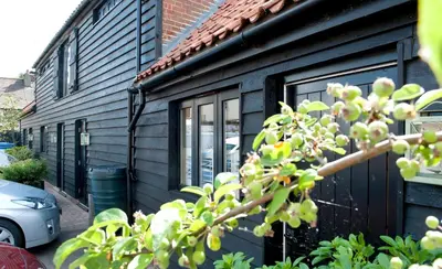 a black house with a tree in front of it at The Fox by Greene King Inns in Bury Saint Edmunds