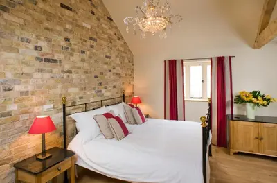 a bedroom with a white bed and a brick wall at The Fox by Greene King Inns in Bury Saint Edmunds