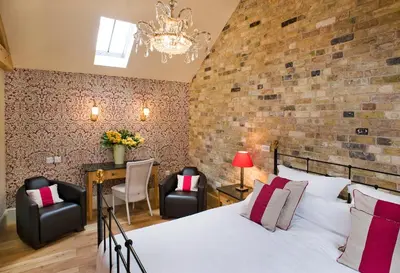 a bedroom with a large bed and two chairs at The Fox by Greene King Inns in Bury Saint Edmunds