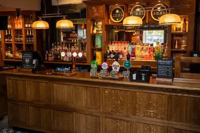 a bar with a lot of bottles of alcohol at The Fox by Greene King Inns in Bury Saint Edmunds
