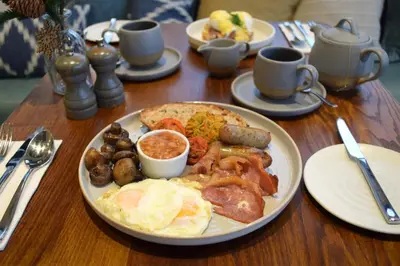 a wooden table with a plate of breakfast food at The Fox by Greene King Inns in Bury Saint Edmunds