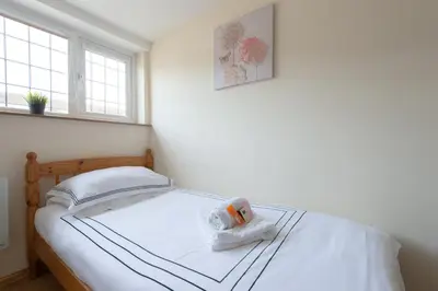 a small bedroom with a bed with white sheets at Simple Private Studio in Harold Wood