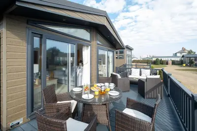 a patio with a table and chairs on a deck at Hunky-Dory - Aldeburgh Coastal Cottages in Sizewell