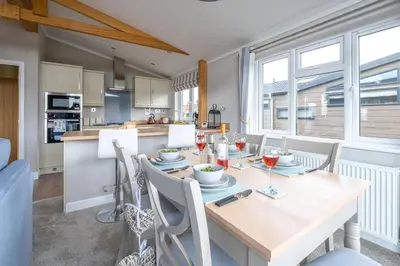 a kitchen and dining room with a wooden table and chairs at Hunky-Dory - Aldeburgh Coastal Cottages in Sizewell
