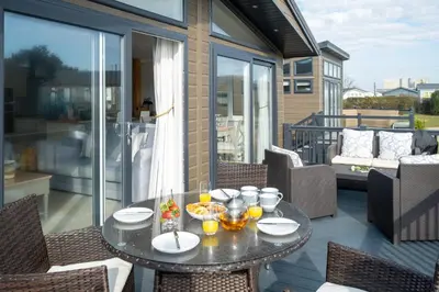 a table and chairs on a balcony with a table and drinks at Hunky-Dory - Aldeburgh Coastal Cottages in Sizewell