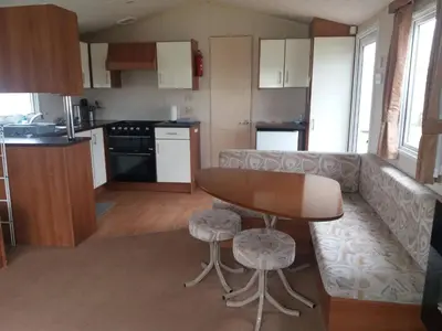 a kitchen and living room with a table and a couch at 2013 Willerby Sunset Static Caravan Holiday Home in Clacton-on-Sea