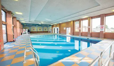 a large swimming pool with blue water in a building at 2013 Willerby Sunset Static Caravan Holiday Home in Clacton-on-Sea