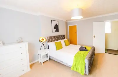 a bedroom with a white bed and a white dresser at 4 Bed - 2 Baths 1 Walk In Shower Lots Of Parking in Ipswich