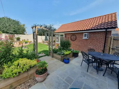 a patio with a table and chairs in a backyard at The Garden Room in Leiston