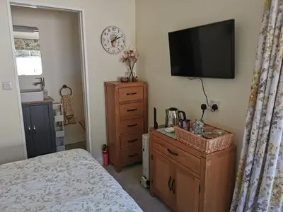 a bedroom with a television and a dresser with a bed at The Garden Room in Leiston