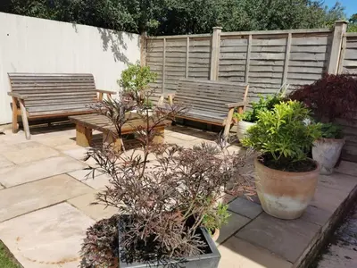 two benches and potted plants on a patio at The Garden Room in Leiston