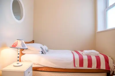 a small bedroom with a bed and a lamp at Tower House, Aldeburgh in Aldeburgh