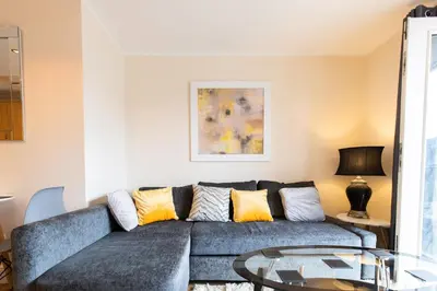 a living room with a blue couch and a glass table at 1-bedroom apartment with balcony, Hoddesdon in Hoddesdon