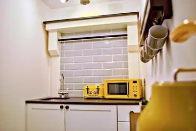 a small kitchen with a yellow microwave on a counter at City Studios in Ely