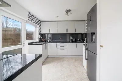 a kitchen with white cabinets and a large window at Skyvillion-STEVENAGE Amazing 3Bed House, Garden, Free Off Street Parking for 2 Cars, WiFi in Stevenage