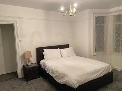 a bedroom with a bed with white sheets and a chandelier at Charming Victoria Conversion Flat in Brentwood with a Garden & Free Parking in Brentwood