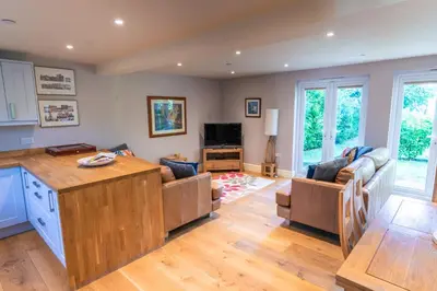 a kitchen and living room with couches and a tv at Garden Villa in Cambridge