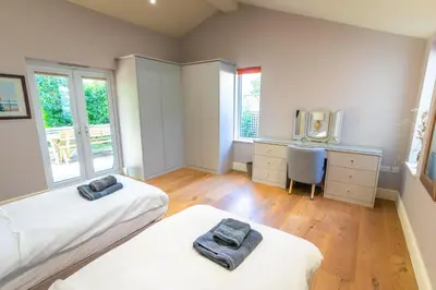 two beds in a room with a desk and a tv at Garden Villa in Cambridge