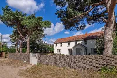 a white house behind a stone fence at Alexander House in Thorpeness