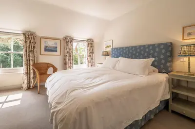 a bedroom with a large bed with a blue headboard at Alexander House 4 in Thorpeness