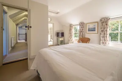 a bedroom with a large white bed and windows at Alexander House 4 in Thorpeness