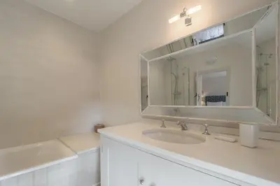 a white bathroom with a sink and a mirror at Alexander House 6 in Thorpeness
