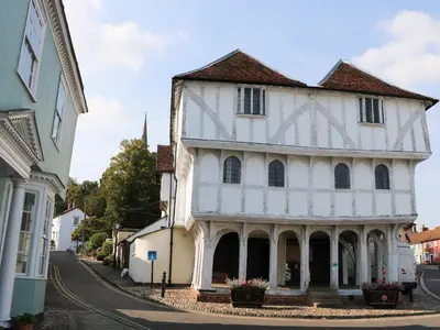 an old white building with a turret on a street at Flink's Barn in Great Dunmow