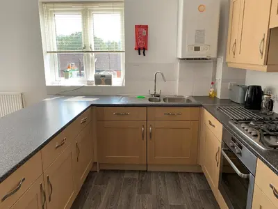 a kitchen with wooden cabinets and a sink and a stove at Toothbrush Apartments - Central Ipswich - Nr Train Station in Ipswich