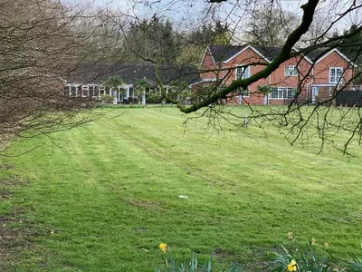 a field of grass with houses in the background at Aldercarr Hall in Attleborough