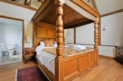 a bedroom with a wooden canopy bed in a room at Old Oak Barn - Beautiful barn conversion with wonderful Jacuzzi hot tub in Stowmarket