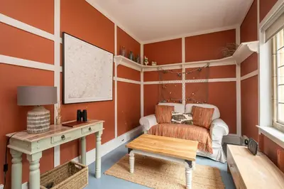 a room with orange walls and a desk and a chair at 1 Westgate in Thorpeness