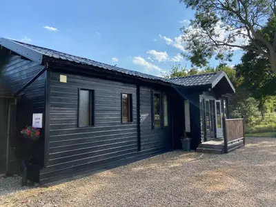 a black tiny house with a black roof at Spacious Garden Lodge at The Chestnuts, Norfolk in Norwich