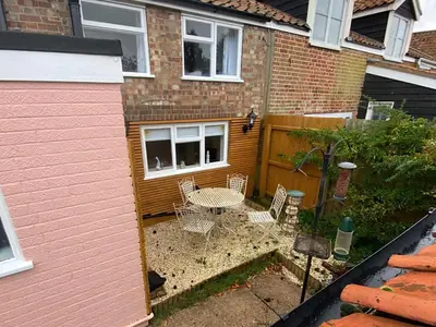 a small backyard with a table and chairs in front of a house at Honey Cottage in Friston