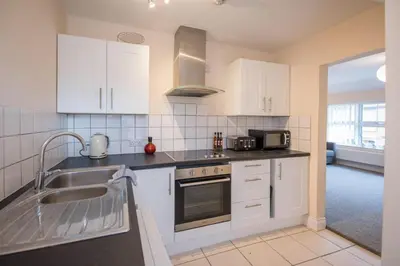 a kitchen with white cabinets and a sink at 2 Abbey Mews, Leiston in Leiston