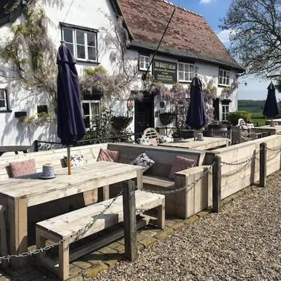 a restaurant with tables and umbrellas in front of a building at The Queen's Head in Hawkedon