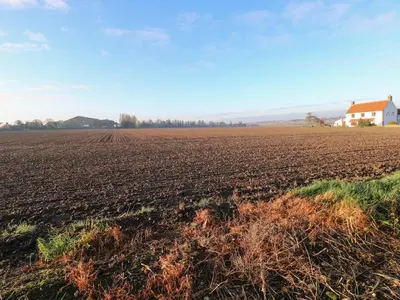 a plowed field with a house in the background at Rose Cottage in Stoke Ferry