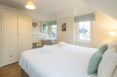 a bedroom with a large white bed and a window at Sanctuary House in Thorpeness