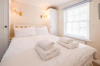 a bedroom with a white bed with towels on it at Admiral Cottage in Aldeburgh