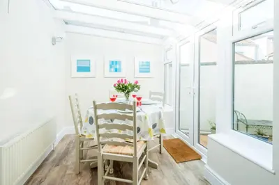 a dining room with a table and chairs and windows at Admiral Cottage in Aldeburgh
