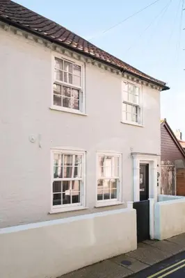 a white house with white windows on a street at Admiral Cottage in Aldeburgh