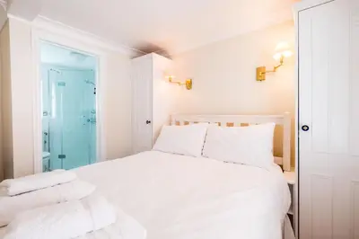 a bedroom with a white bed with towels on it at Admiral Cottage in Aldeburgh