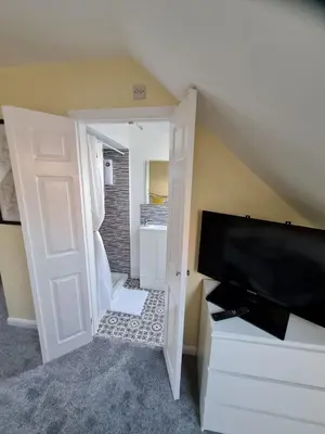 a living room with a flat screen tv and an open door at Self contained annexe in pretty Suffolk village in Bury Saint Edmunds