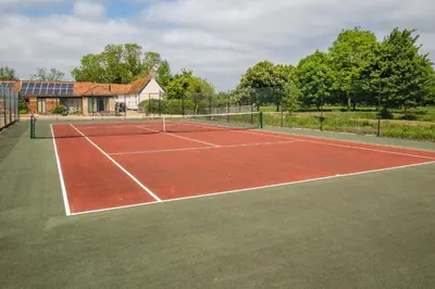 a tennis court in front of a house at East Green Farm Cottages - The Granary in Saxmundham