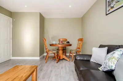 a living room with a table and a couch at Remaj Serviced Accommodation, sleeps 7 & free parking in Laindon
