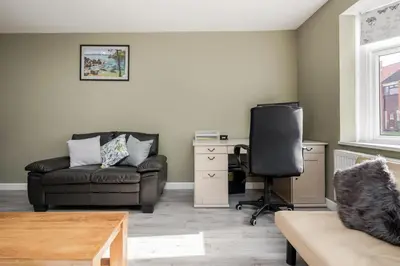 a living room with a couch and a chair at Remaj Serviced Accommodation, sleeps 7 & free parking in Laindon