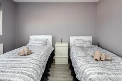 two beds in a bedroom with shoes on them at Remaj Serviced Accommodation, sleeps 7 & free parking in Laindon