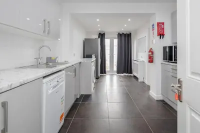 a kitchen with white appliances and a tile floor at Remaj Serviced Accommodation, sleeps 7 & free parking in Laindon