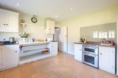 a kitchen with white cabinets and a clock on the wall at 6 Lakeside Avenue in Thorpeness