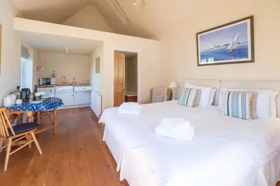 two beds in a room with a table and a kitchen at 6 Lakeside Avenue in Thorpeness